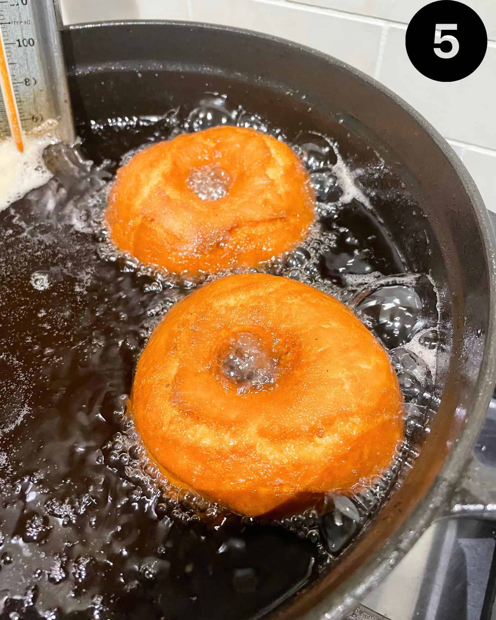 donuts being fried in a large pot.