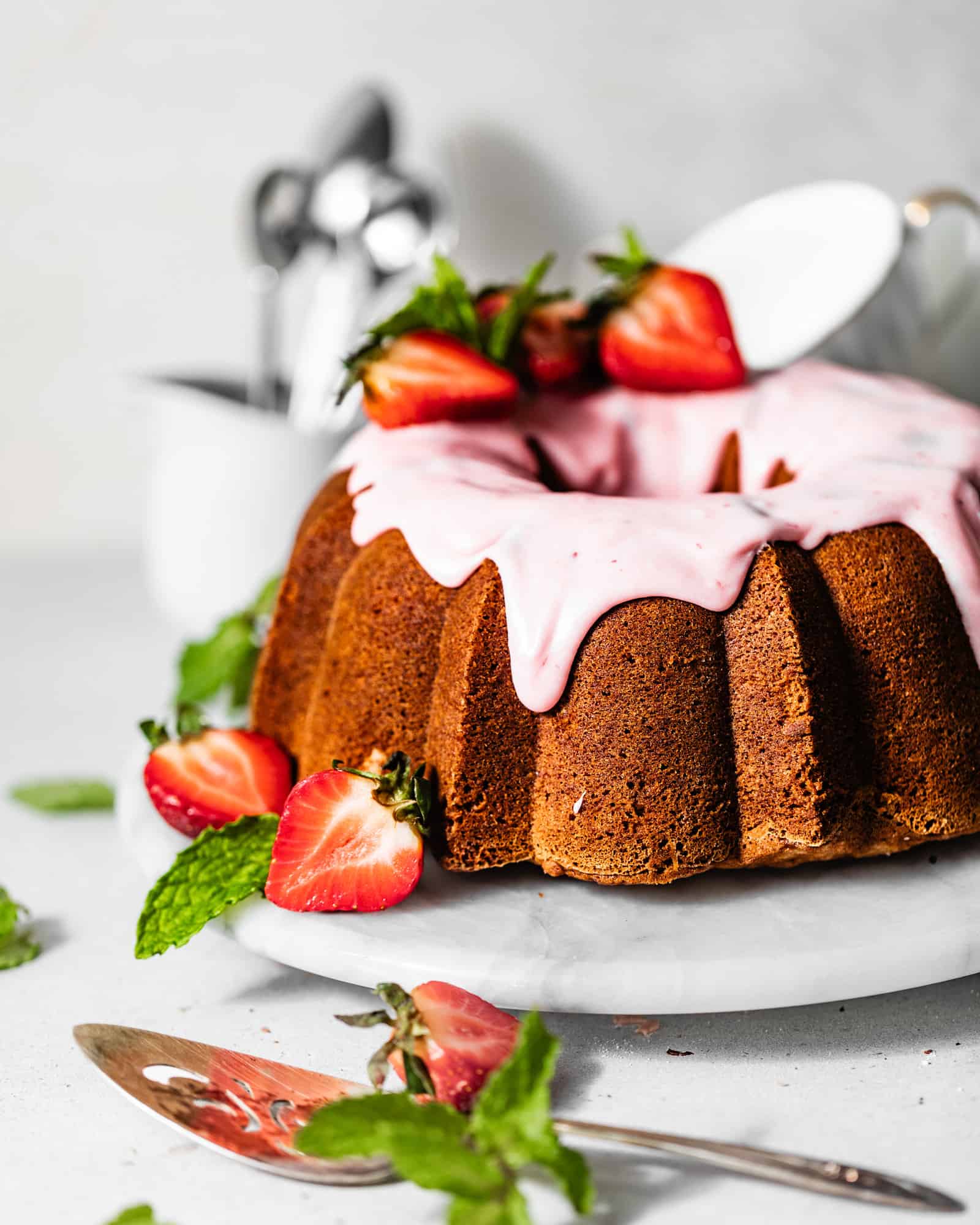 strawberry pound cake on a serving tray garnished with fresh strawberries and strawberry glaze.