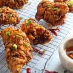 fried chicken on a cooling rack with honey in a bowl