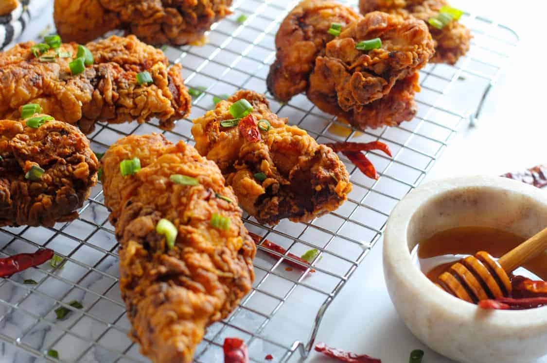 fried chicken on a cooling rack with honey in a bowl