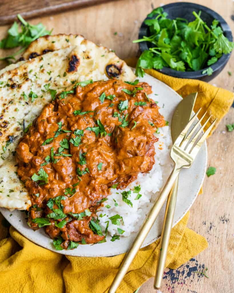Better than takeout butter chicken on a plate with naan and rice