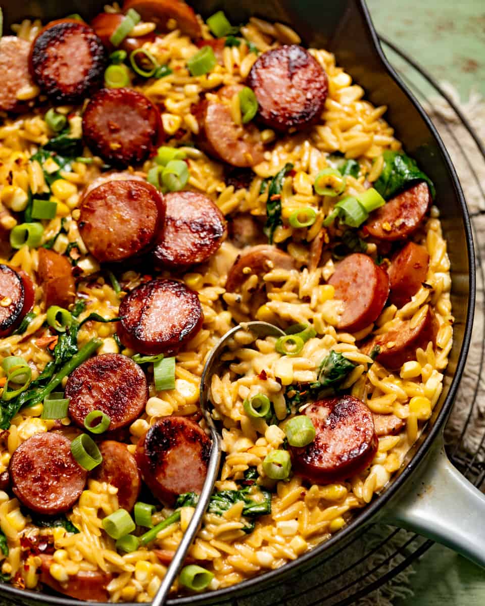 creamy cajun orzo in a skillet with a spoon.