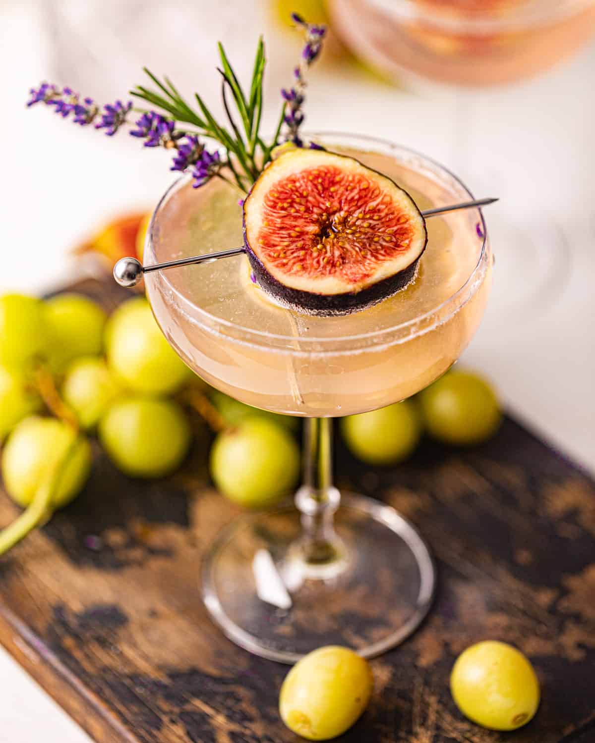 a lavender cocktail in a glass with fresh lavender sprigs.