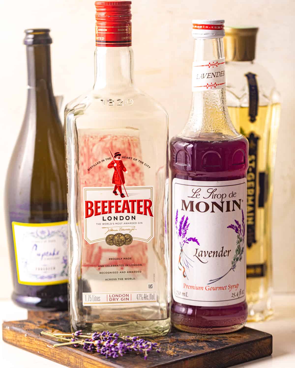 ingredients to make a lavender cocktail - gin, lavender syrup, prosecco, elderflower liqueur, and lime juice.