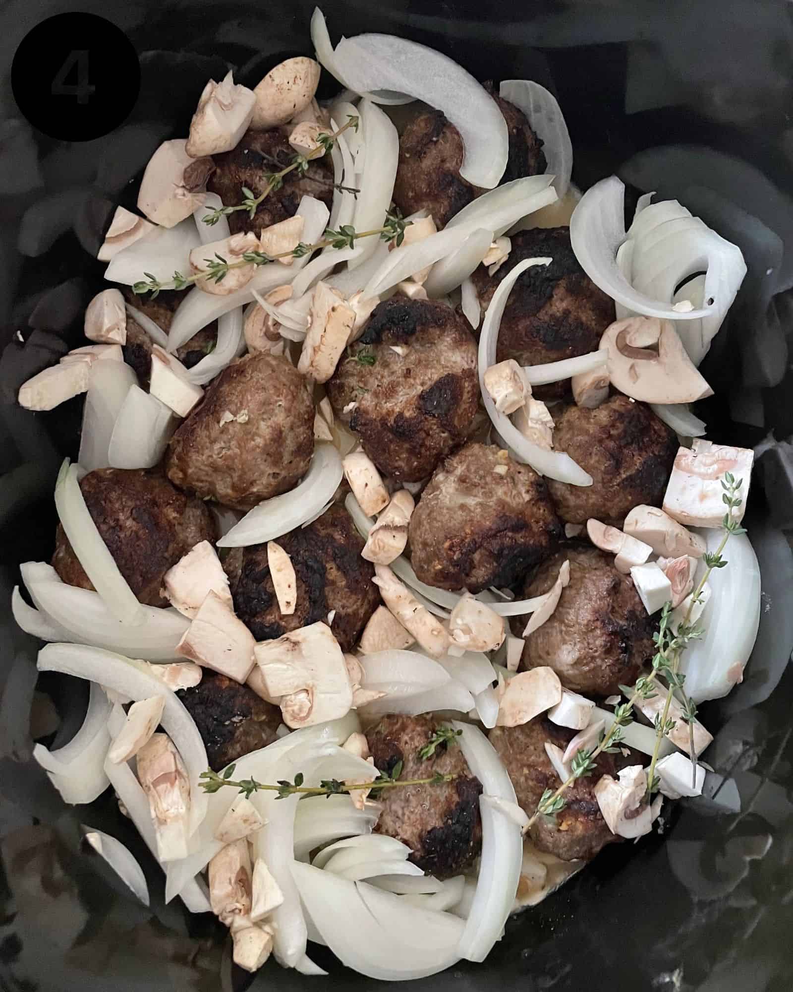 swedish meatballs in a crock pot with onions, thyme, and mushrooms.