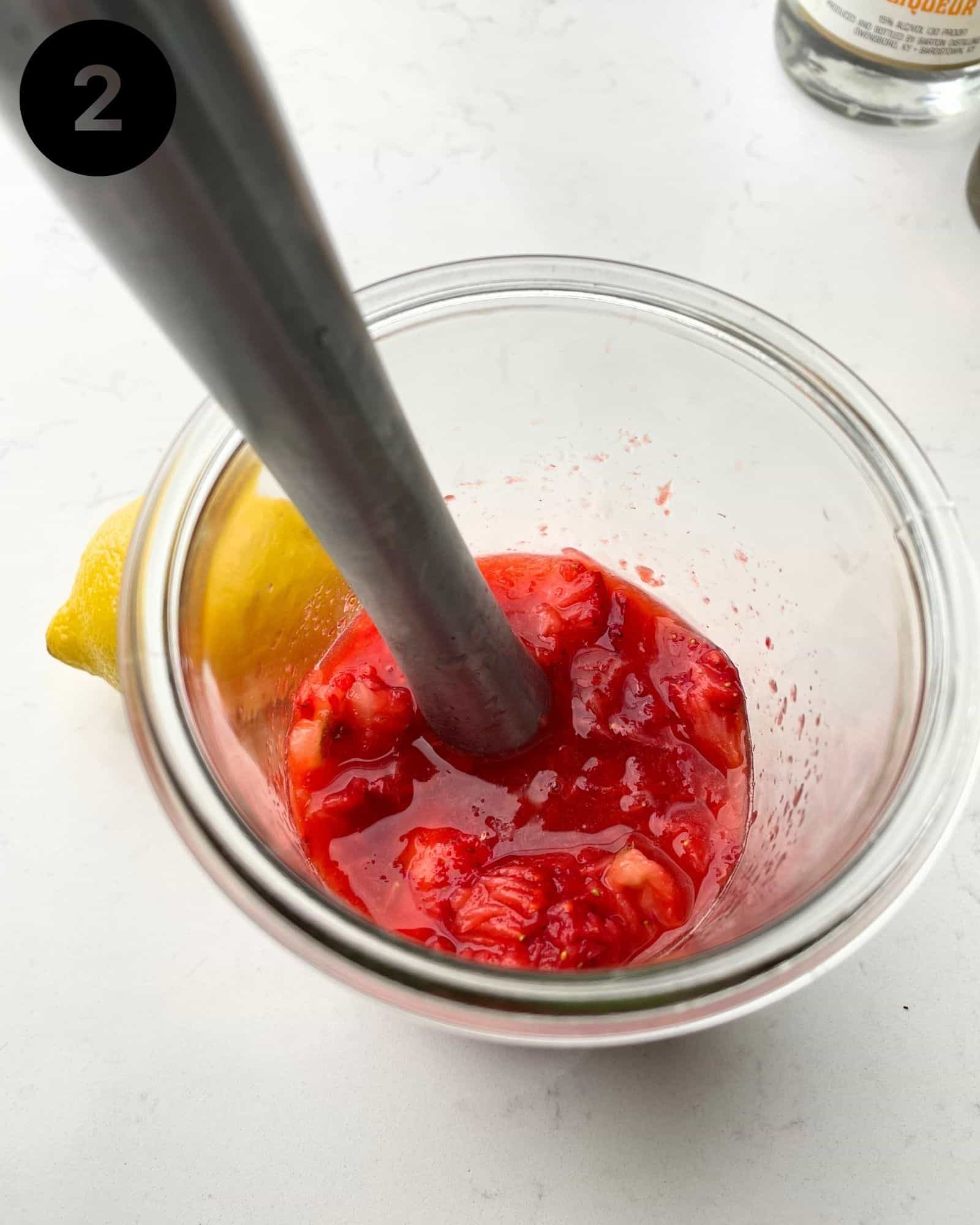 strawberries and lemon juice muddled together in a glass jar.