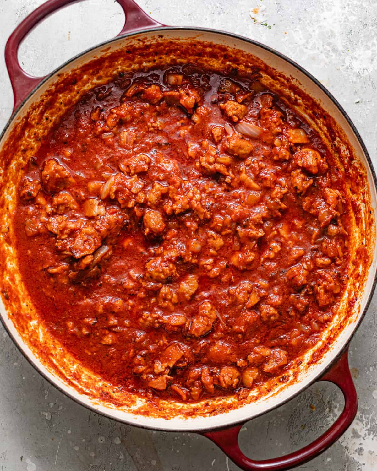 tomato sauce cooked in a skillet with italian sauce, bacon, chopped veggies, and fresh herbs. 