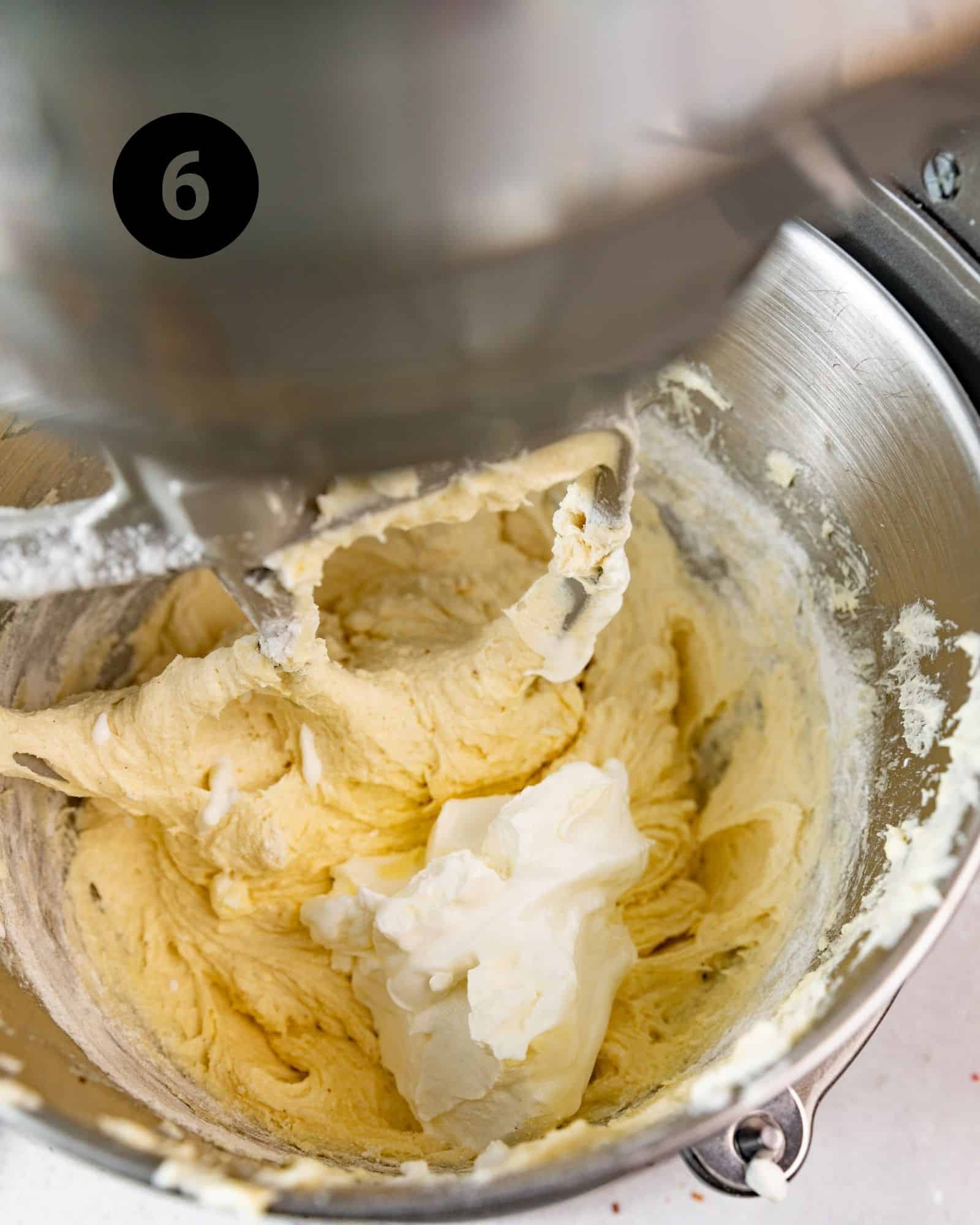 sour cream and milk added to the cake batter in a stand mixer.
