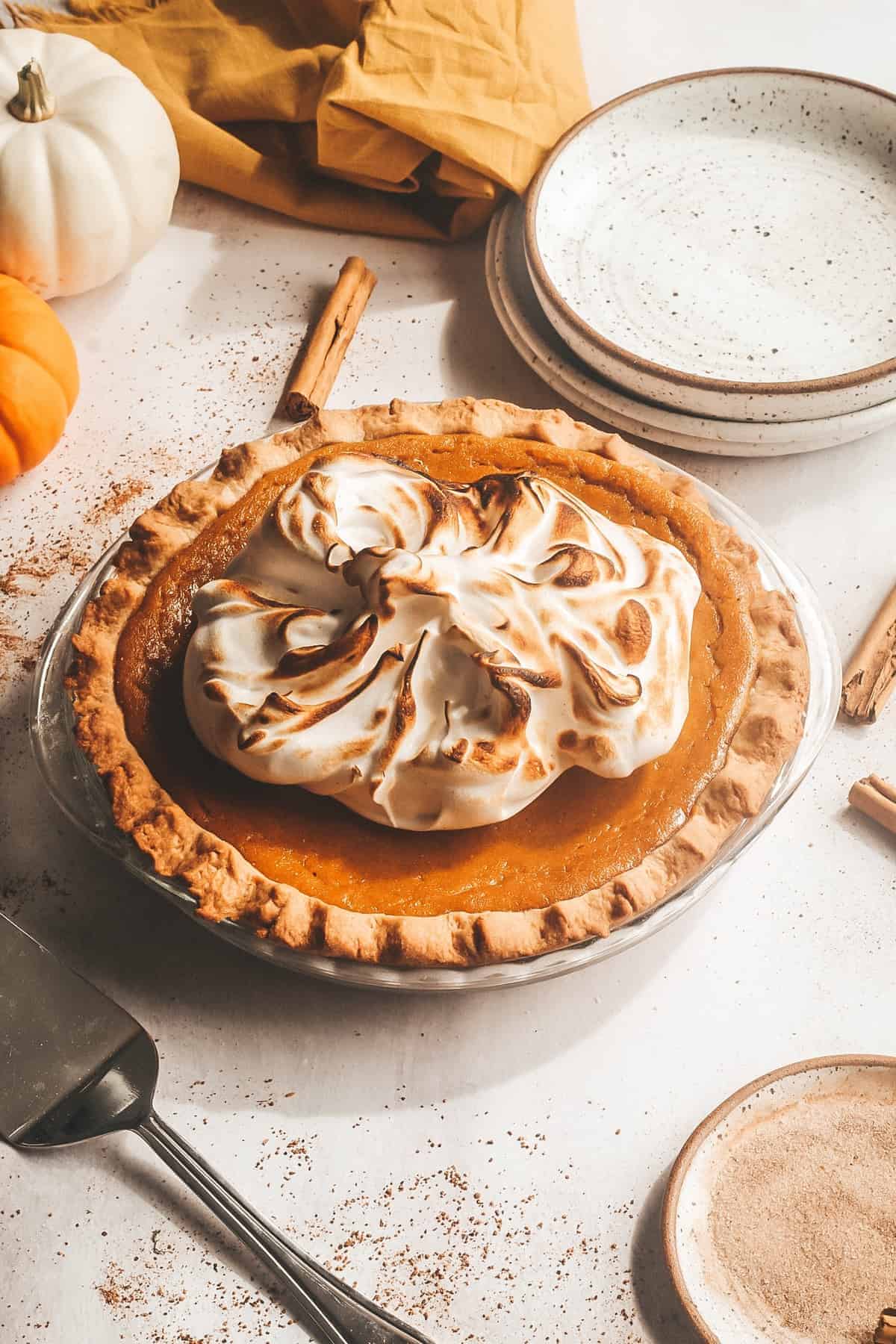 Sage Browned Butter Pumpkin Pie with plates and pumpkins in the background