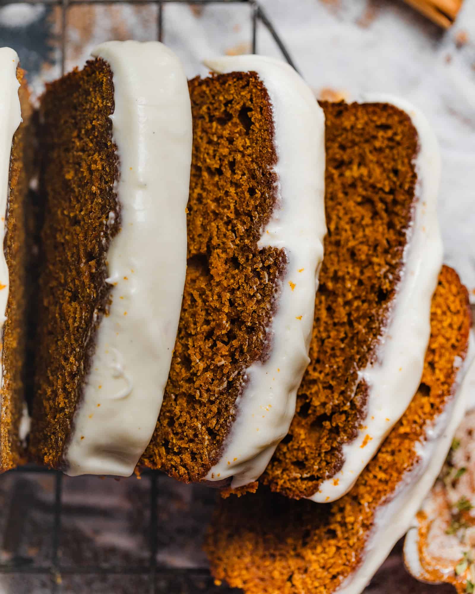 sliced pumpkin bread on a wire rack with cream cheese icing on top