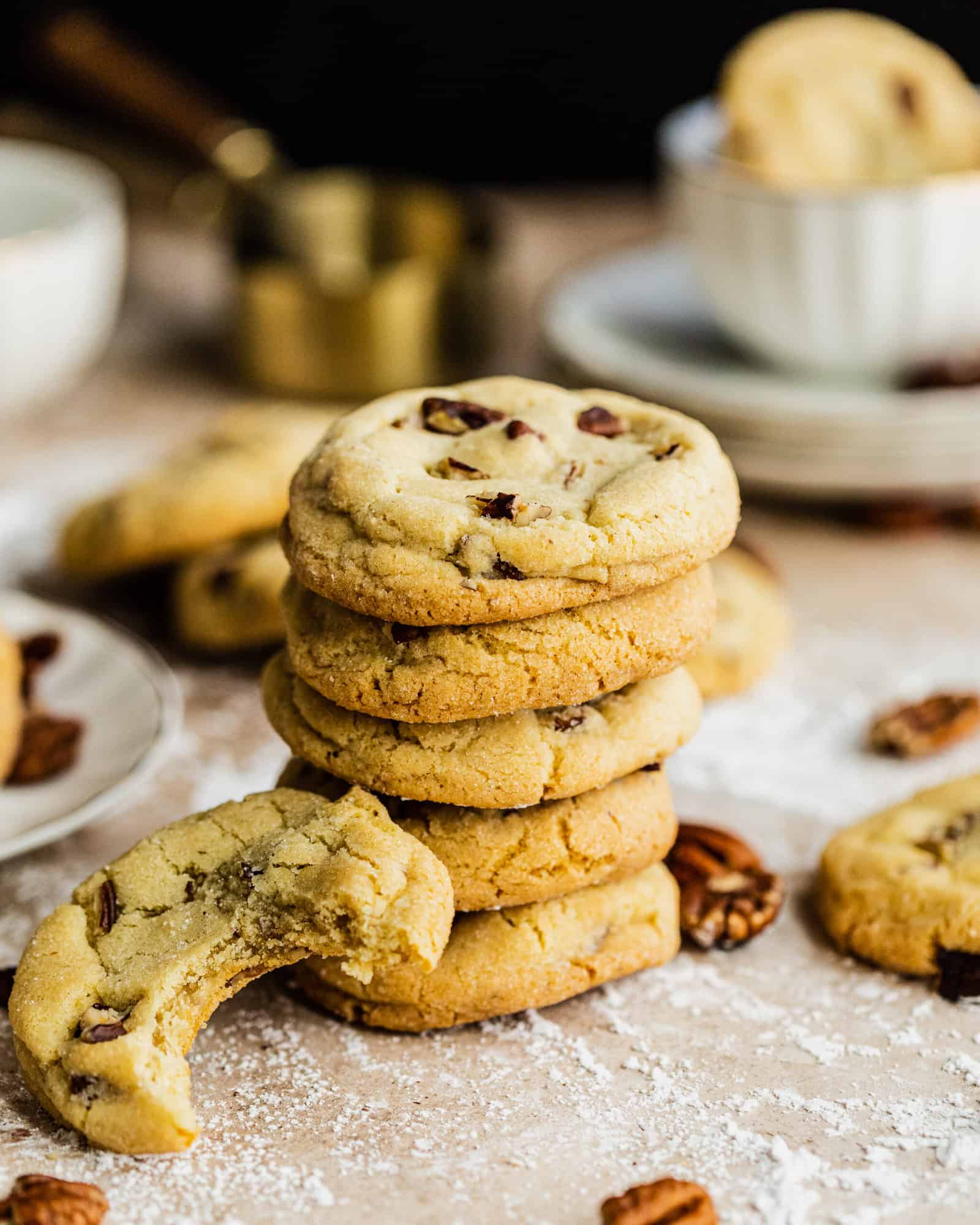 Vanilla Bean Butter Pecan Cookies stacked on top of each other with cookies around the stack 