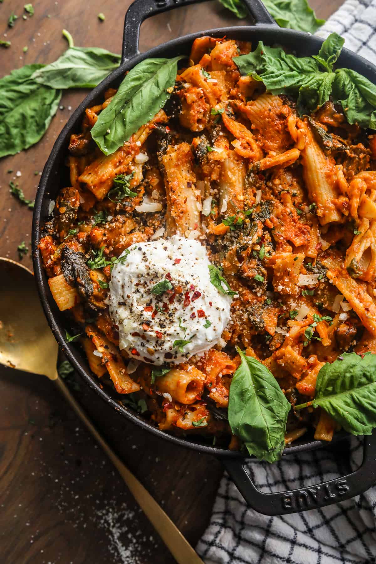 one pot creamy tomato pasta with a serving spoon on a wooden surface