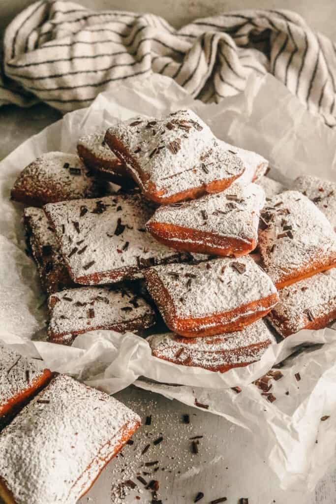 beignets on parchment paper with powdered sugar