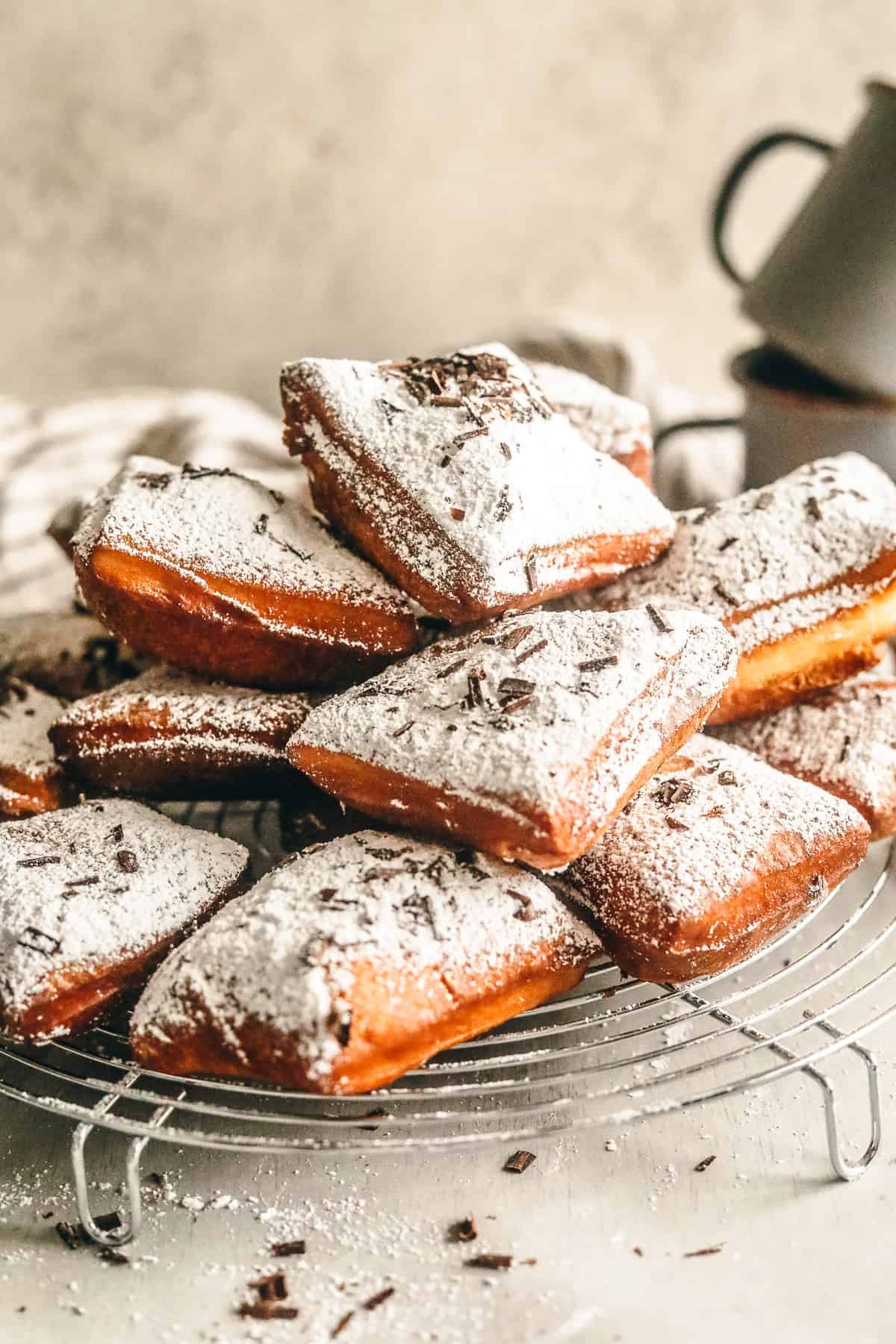 new orleans style beignets on a rack with a coffee mug