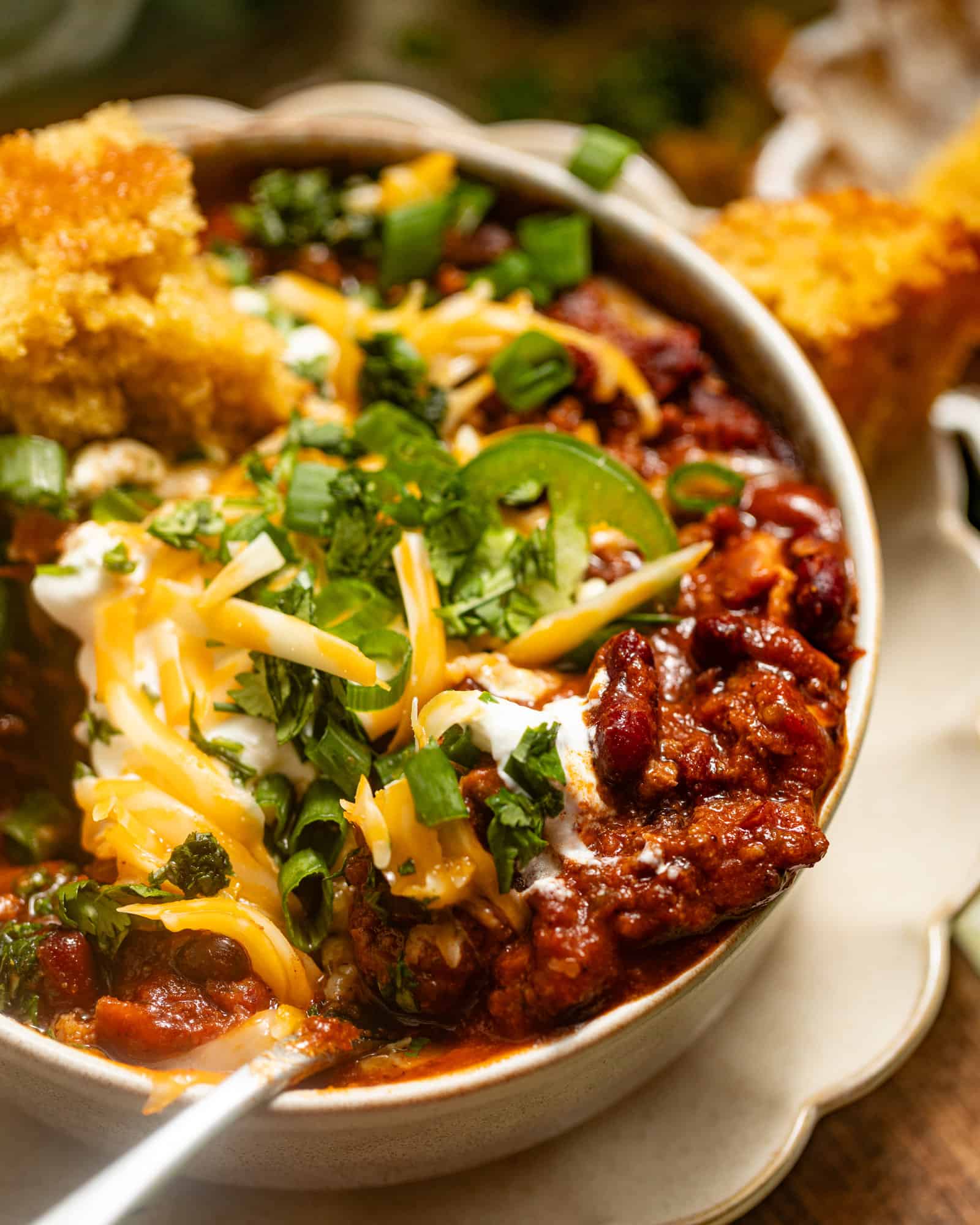 an up close photo of chili on a spoon with cheese and cilantro.