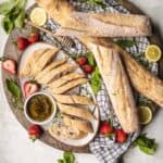 baguettes on a cutting board with strawberries and dipping oil
