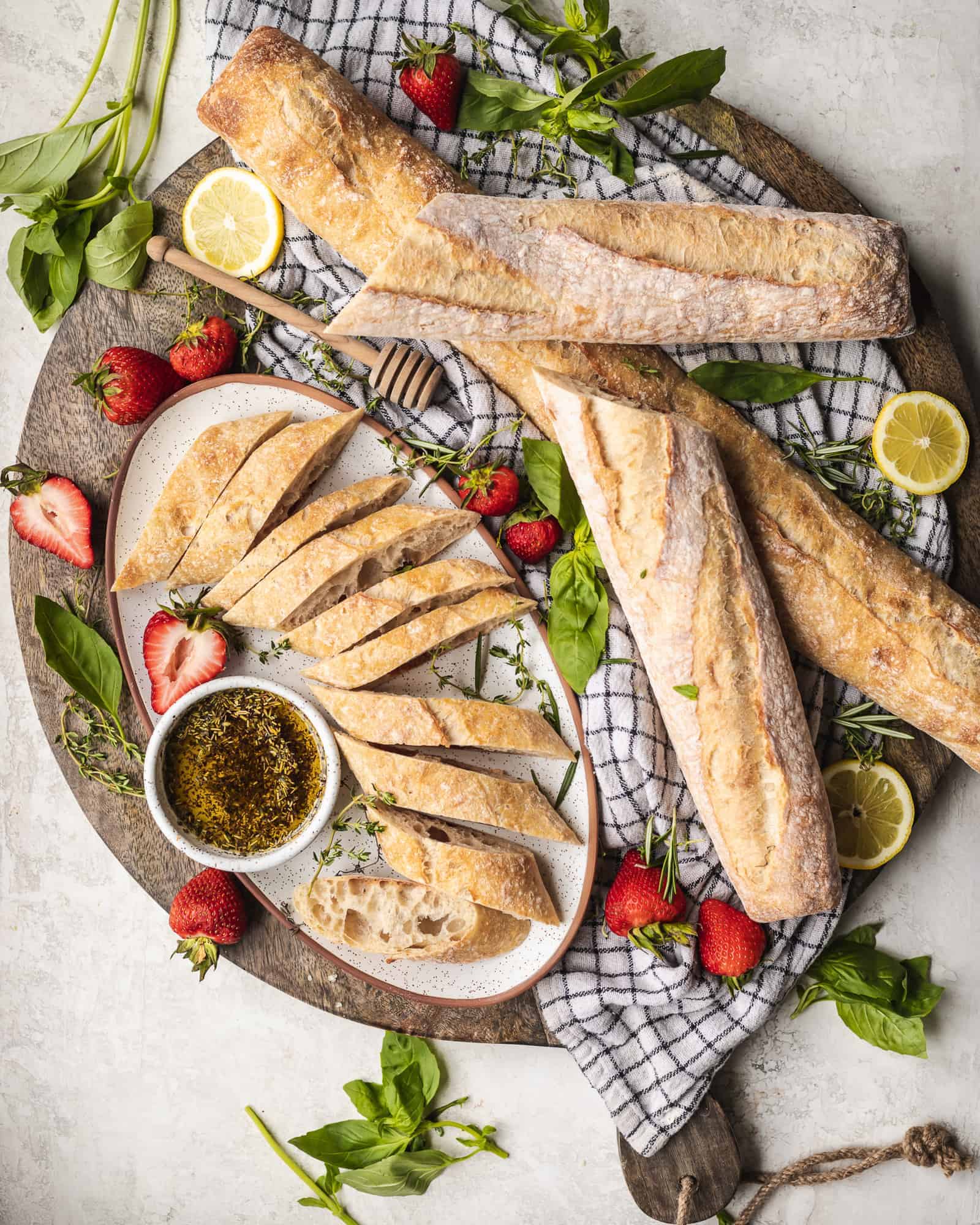 baguettes on a cutting board with strawberries and dipping oil