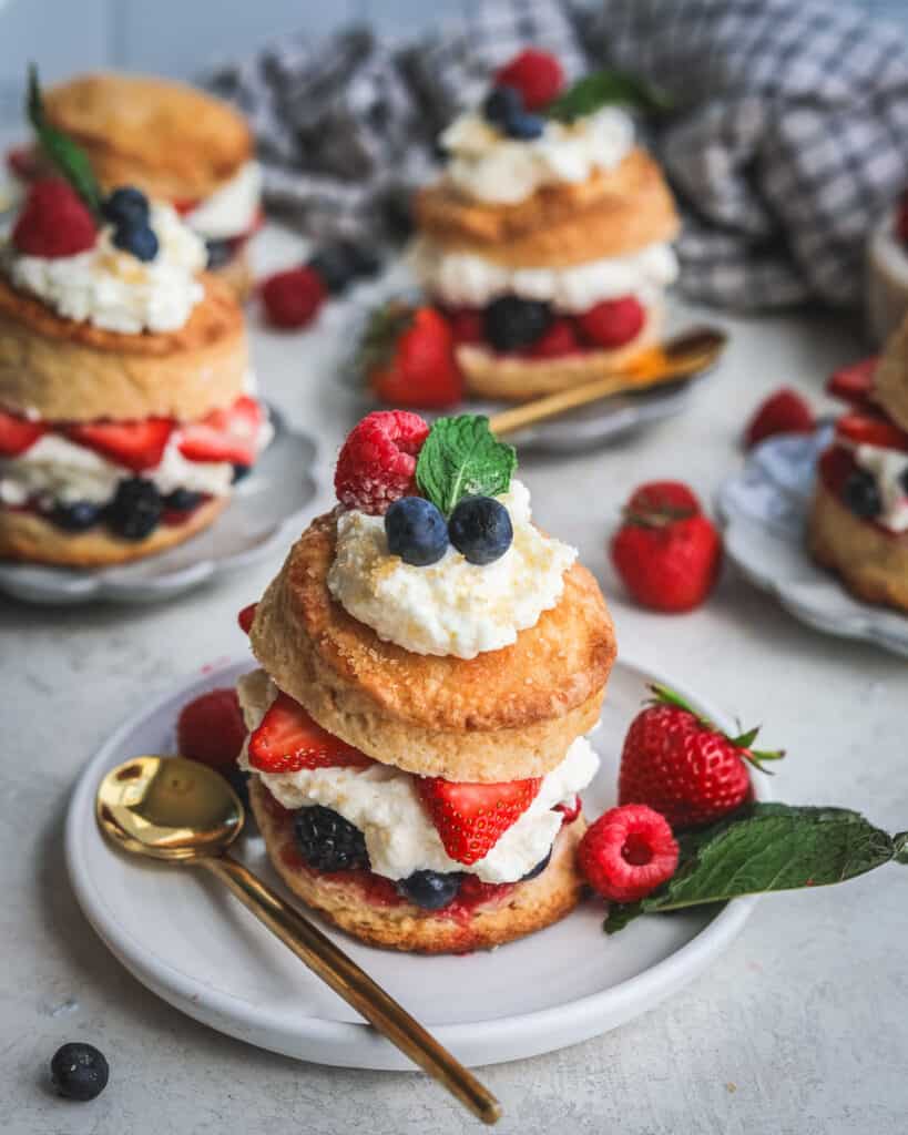 Mixed Berry Shortcakes with whipped mascarpone cream on a plate with a spoon