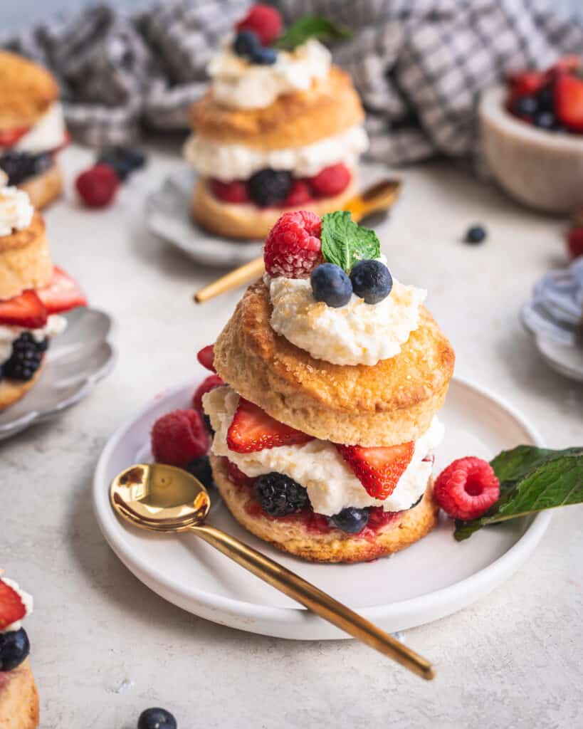 Mixed Berry Shortcakes with whipped mascarpone cream on a plate with a spoon