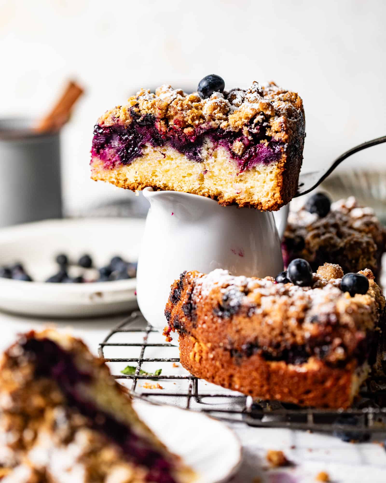 blueberry sour cream coffee cake on a cake server on top of a cup.