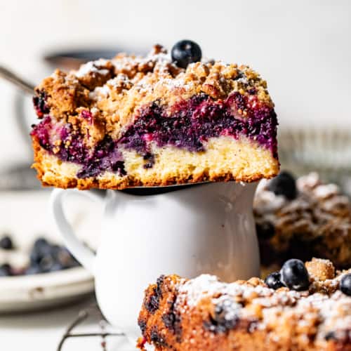 a slice of blueberry coffee cake sitting on top of a small cup.
