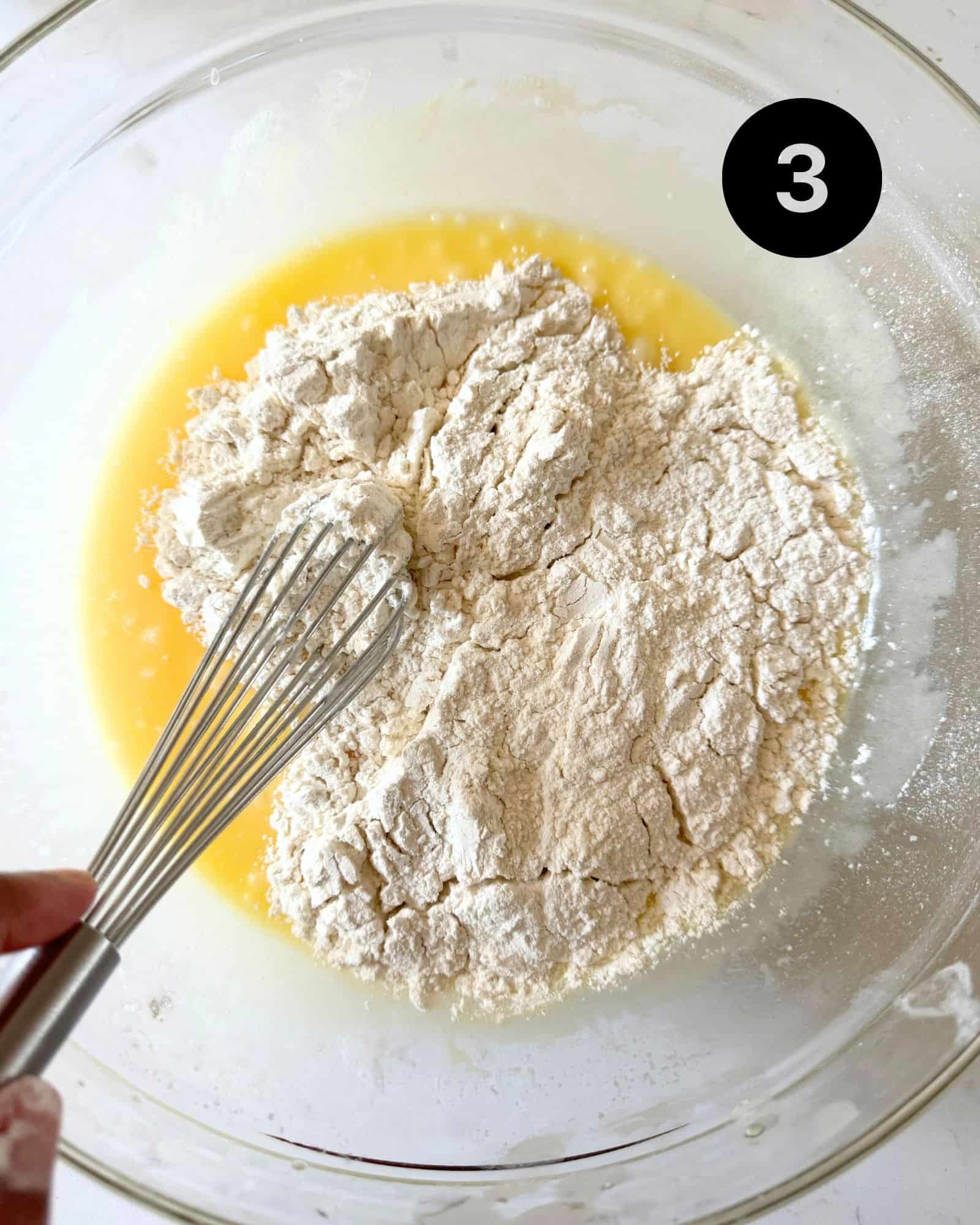 wet ingredients and dry ingredients mixed together in a bowl with a whisk.