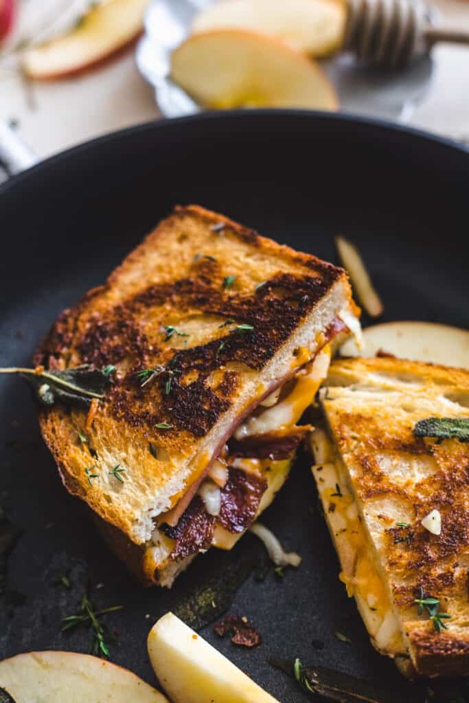 apple bacon cheddar grilled cheese cut in half and placed on top of each other