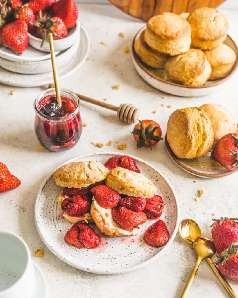 Honey Buttermilk Biscuits on a plate with strawberries and biscuits surrounding the plate