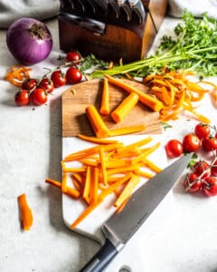 Julienne carrots on cutting board with a knife