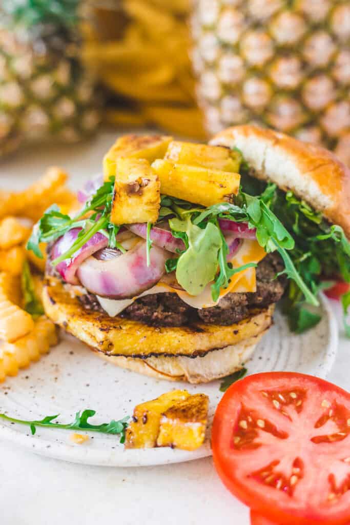 burger and fries on a plate with pineapples in the background