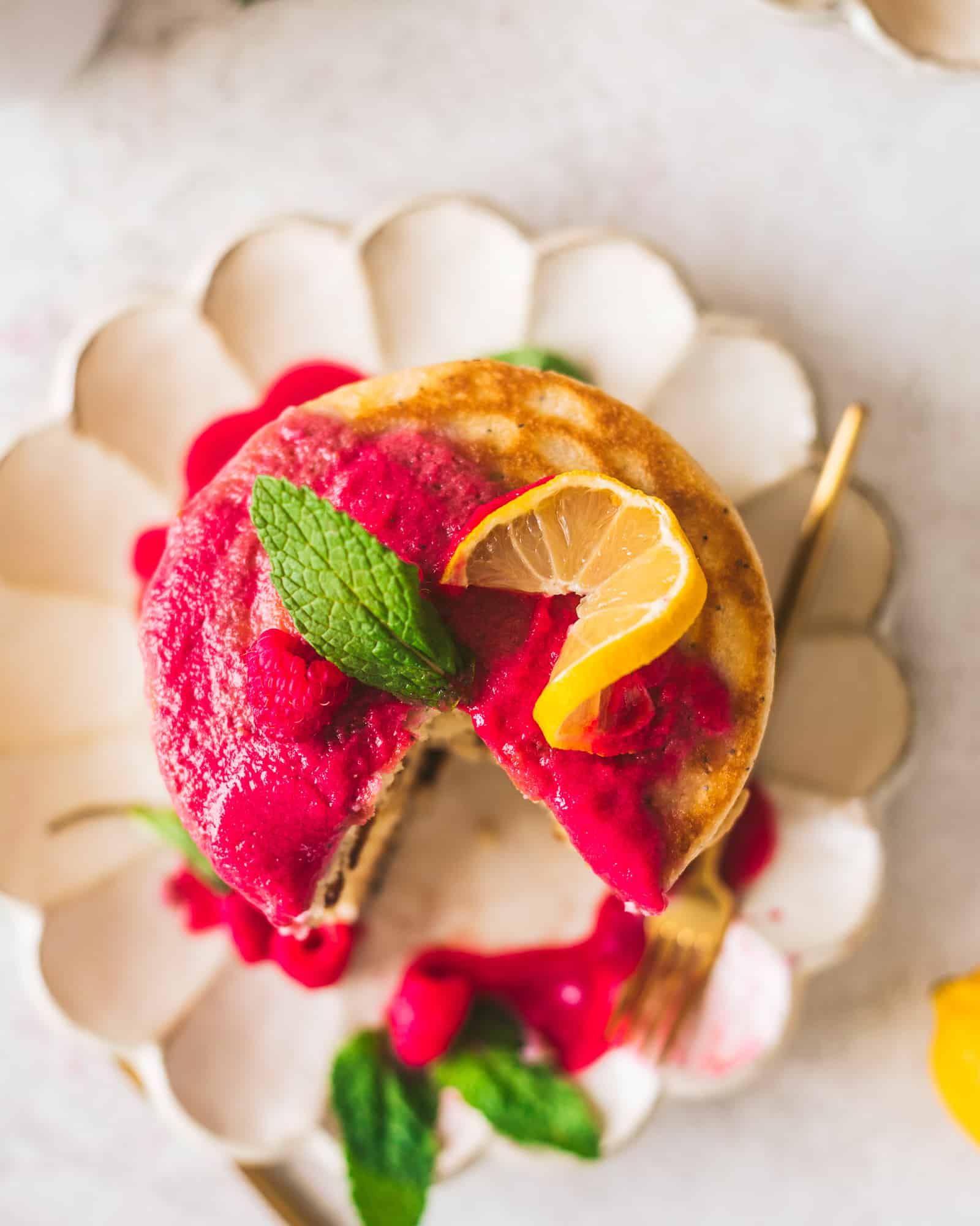 Lemon poppyseed pancakes on a plate with lemons and raspberries