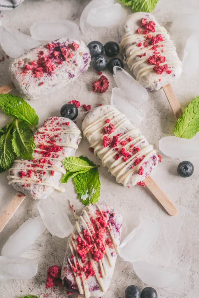 blueberry cobbler ice cream bars on a white surface with ice and berries