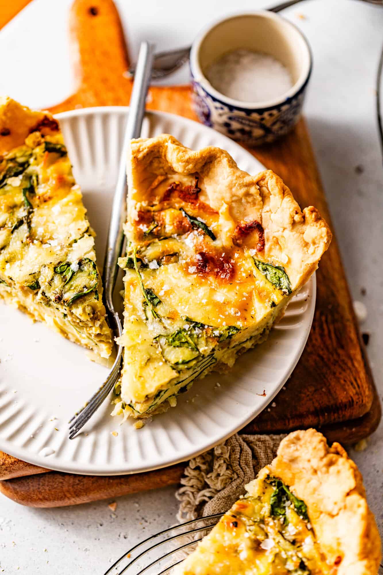 two slices of quiche florentine on a plate with a fork.