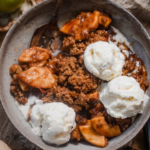 apple crisp without oats in a bowl showing the crisp crumble topping with juicy apples underneath.