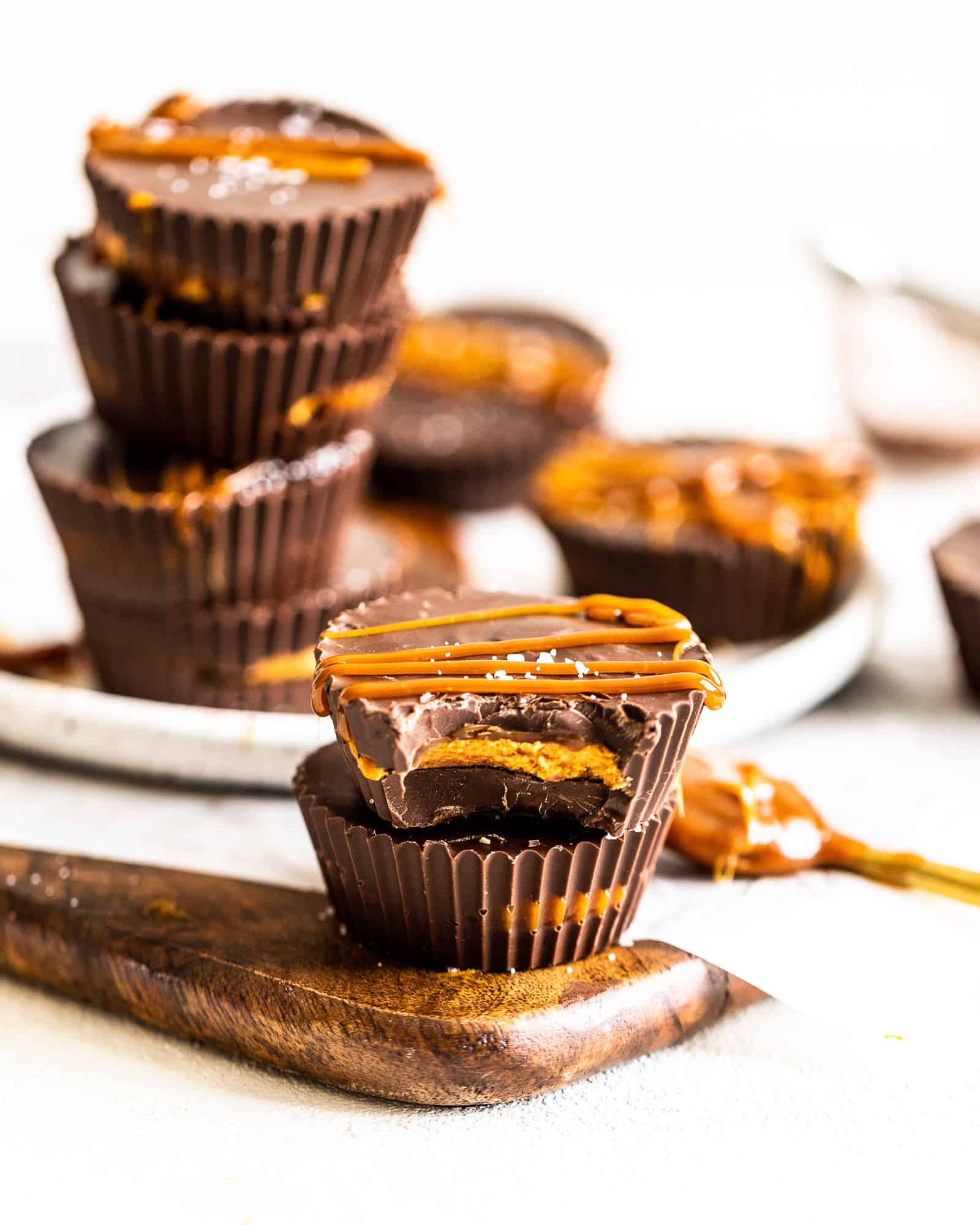 salted caramel peanut butter cups stacked up on top of each other with more peanut butter cups in the background