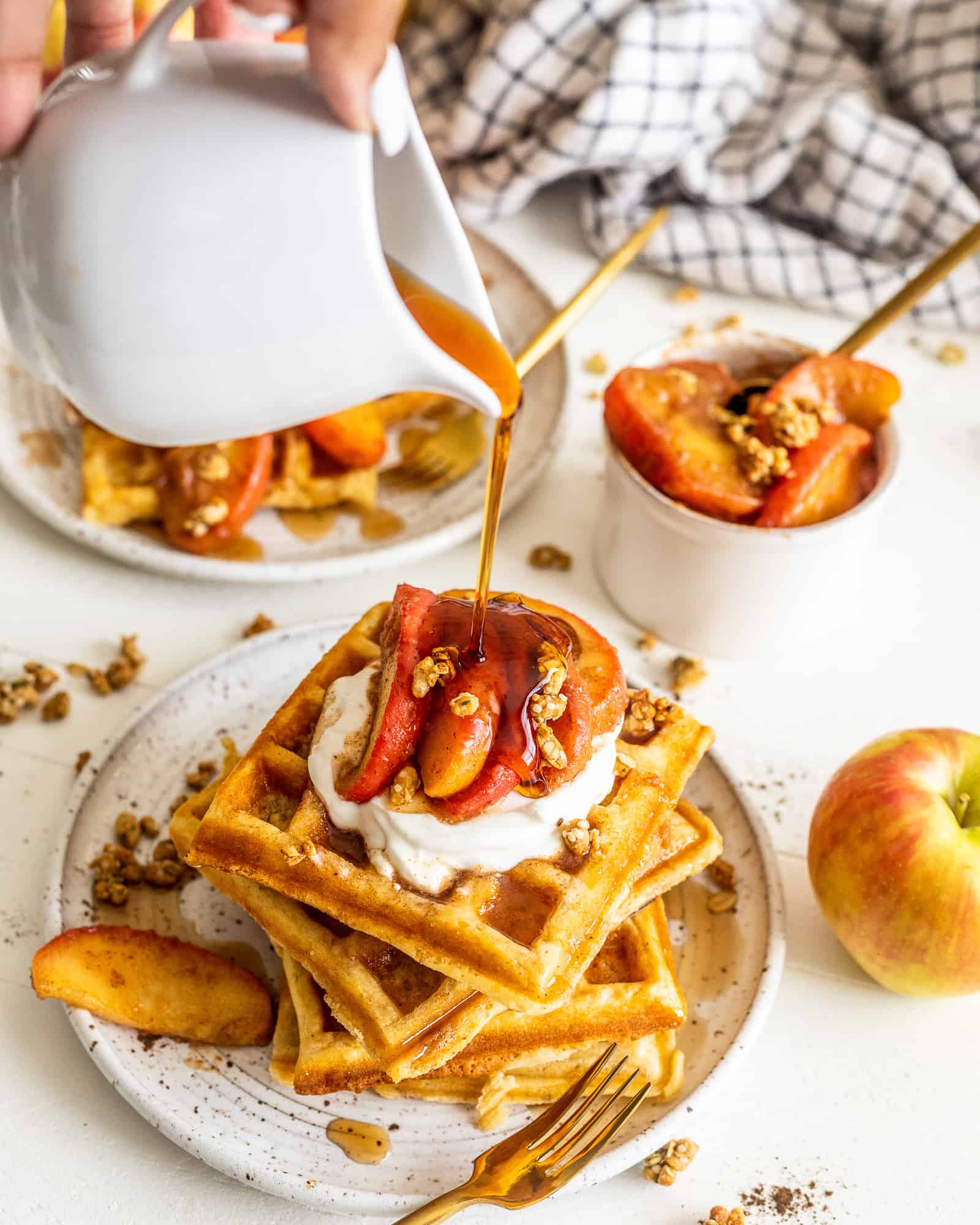 pouring syrup on top of waffles with cinnamon apples