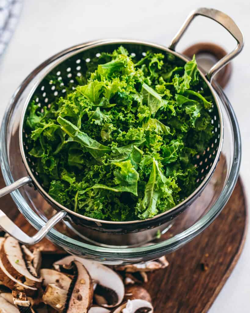 kale is a colander with mushrooms to the side