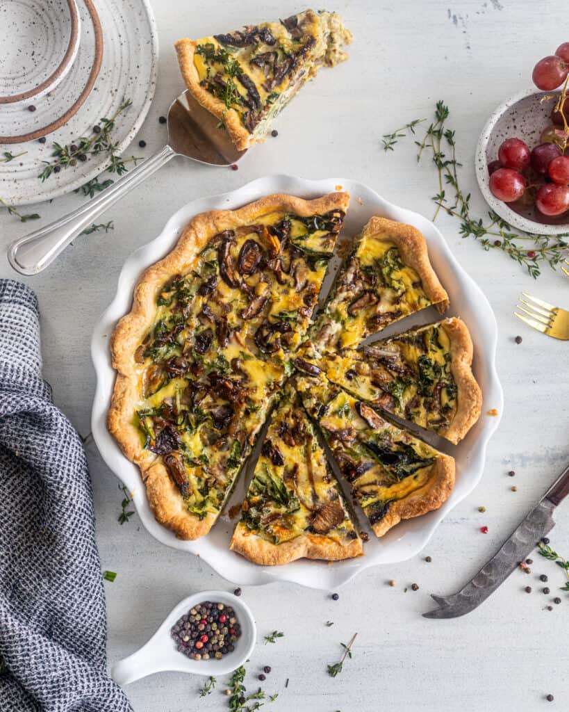 overhead photo of kale and mushroom quiche with a slice cut out 