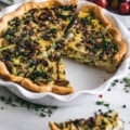 Kale and Mushroom quiche in a pie pan with a slice cut out of it