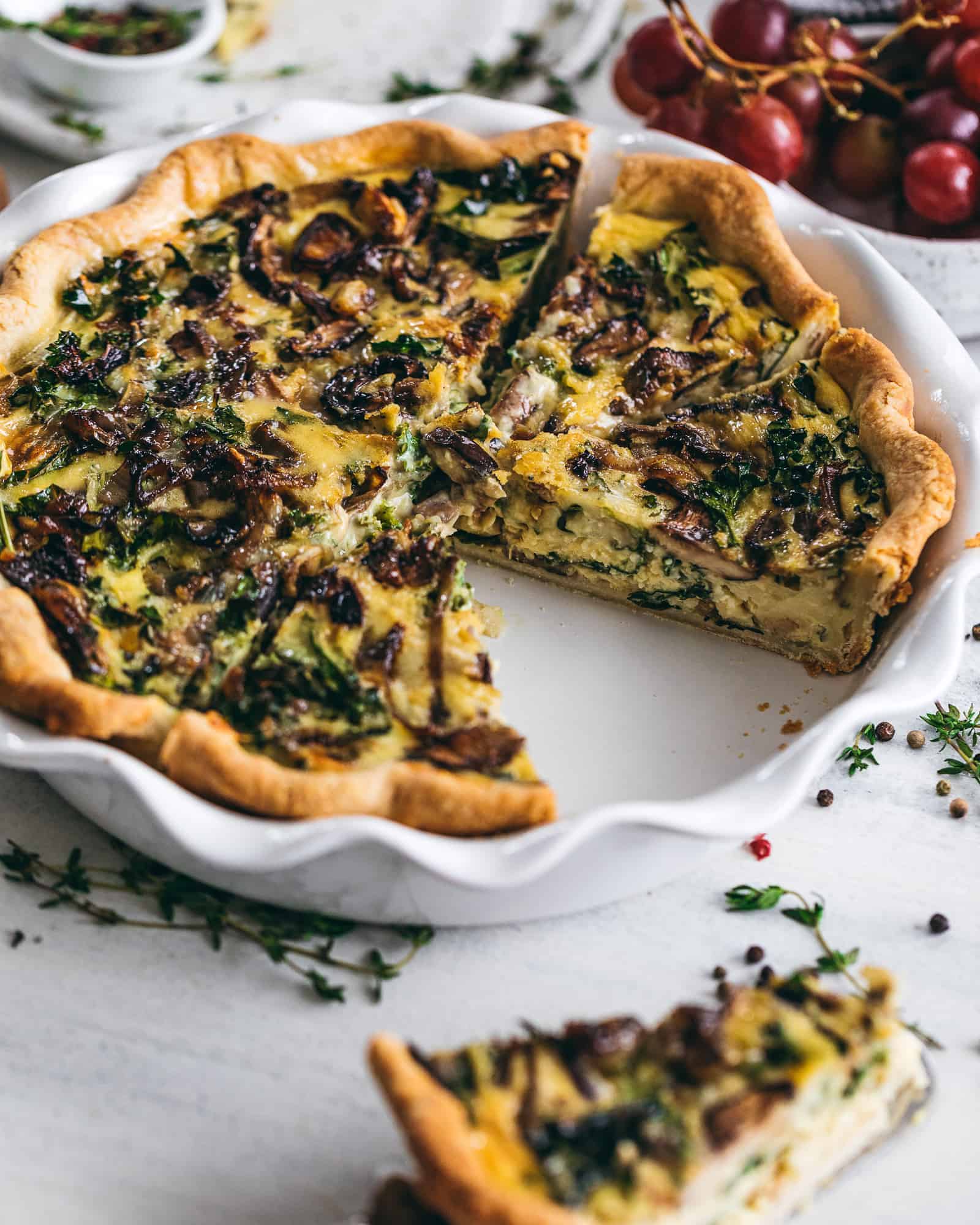 Kale and Mushroom quiche in a pie pan with a slice cut out of it