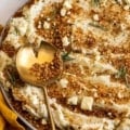 Close up view of a bowl of Blue Cheese Mashed Potatoes with Toasted Breadcrumbs with a gold spoon contains more breadcrumbs on top.