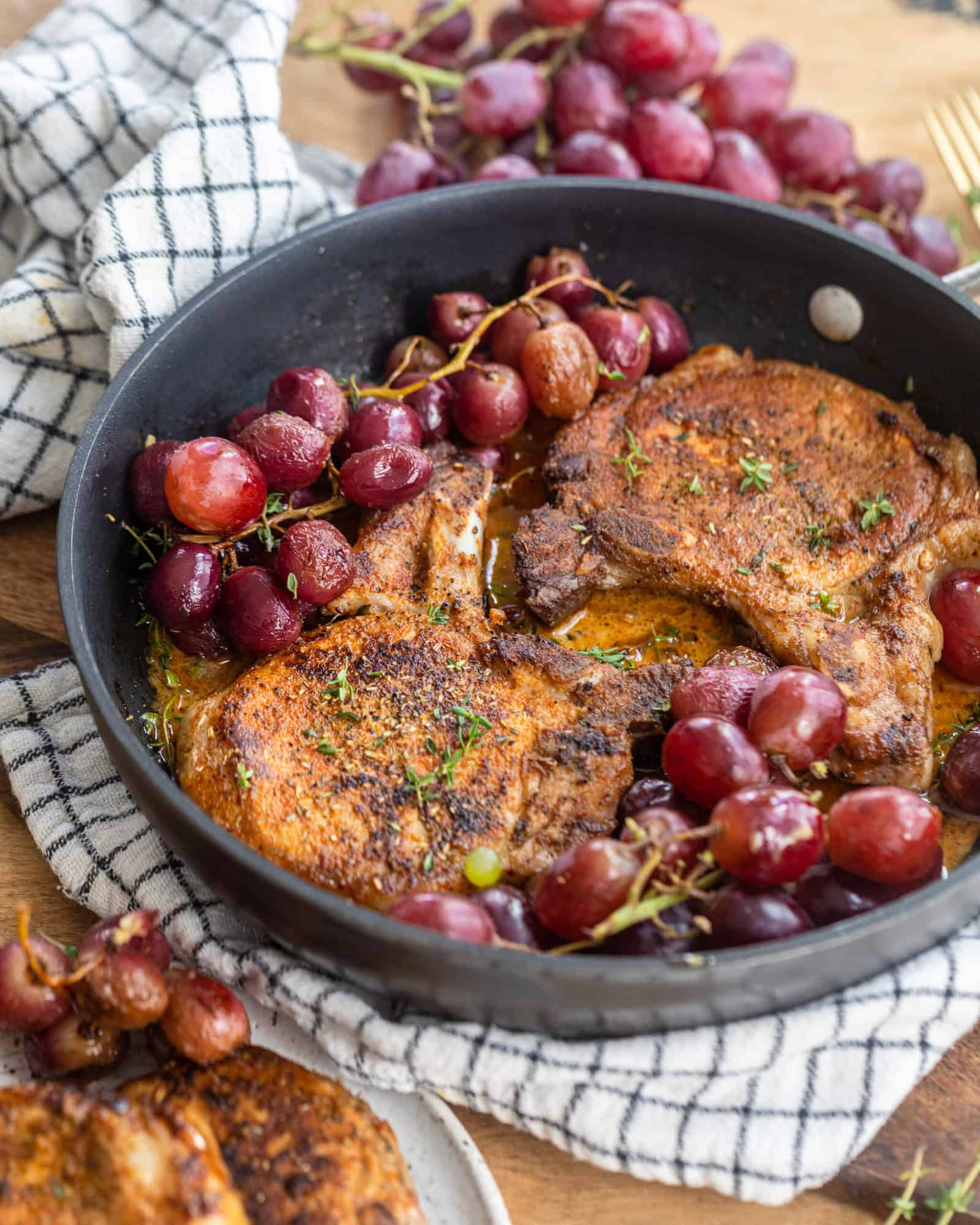 Pork chops in a pan with roasted grapes