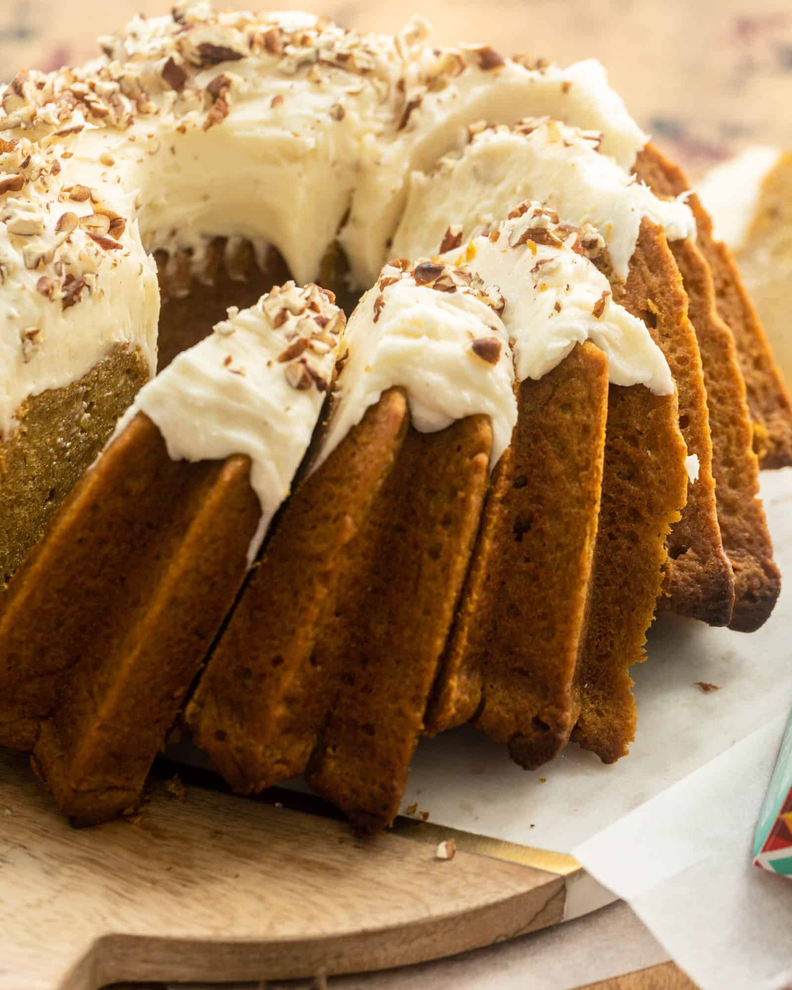 Close up view of sliced Pound Cake with Cream Cheese Frosting garnished with chopped walnuts.