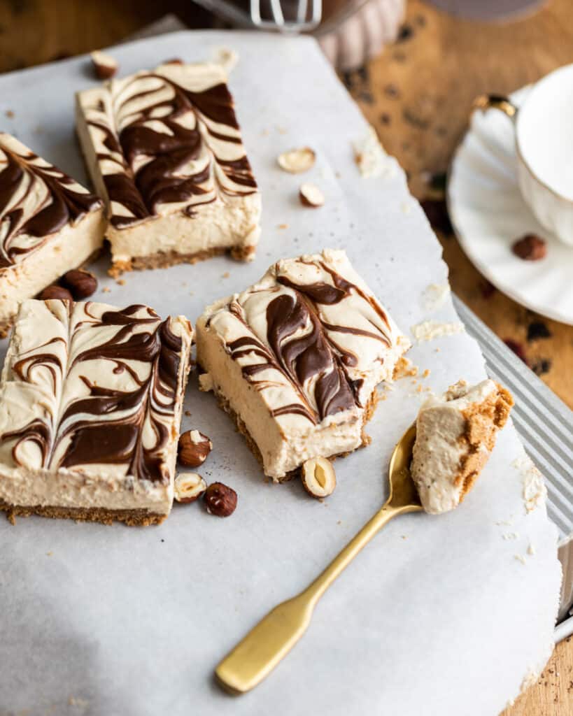 mocha peanut butter cheesecake bars on a piece of parchment paper with a spoon