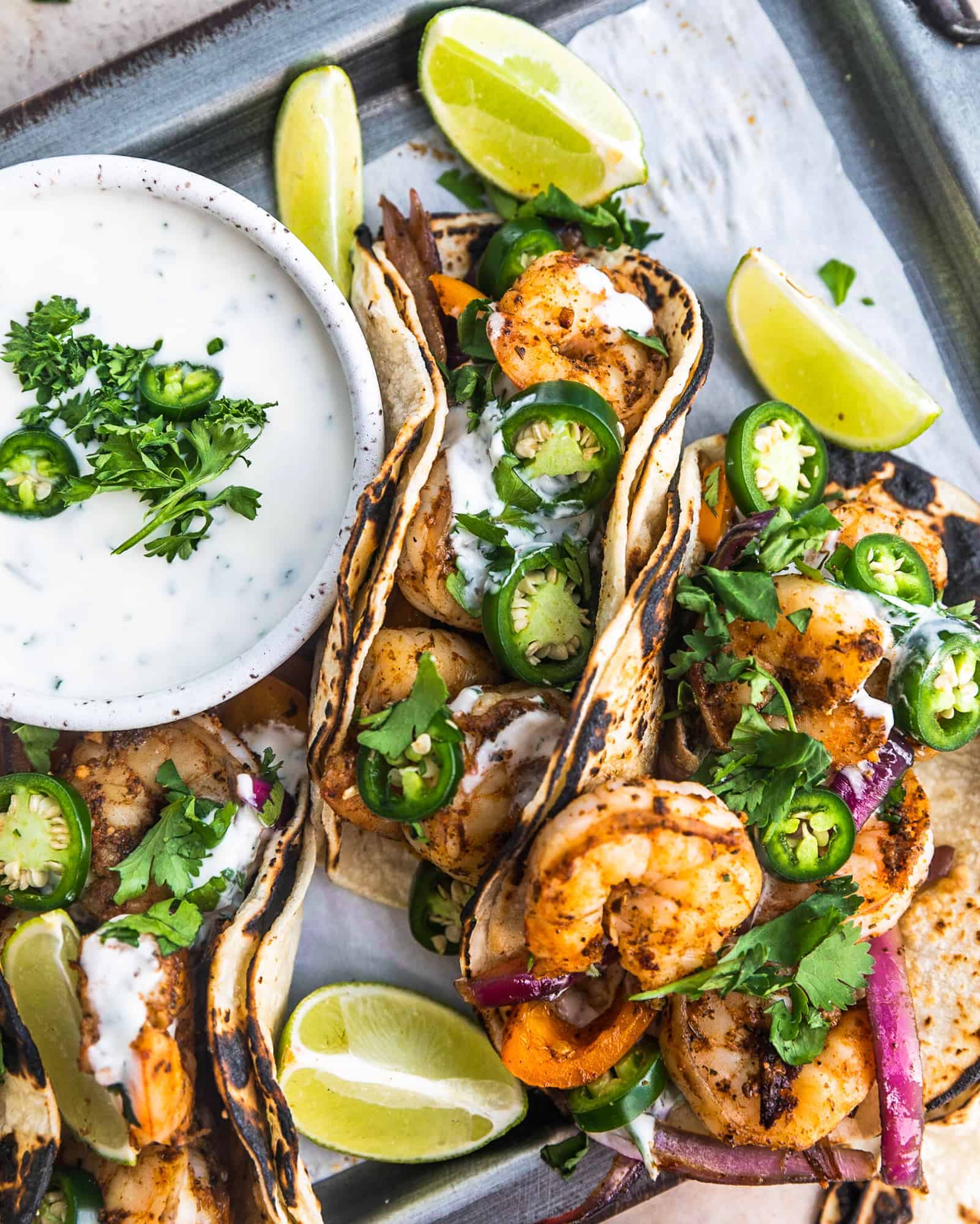 cajun shrimp tacos on a serving tray with limes and ranch sauce