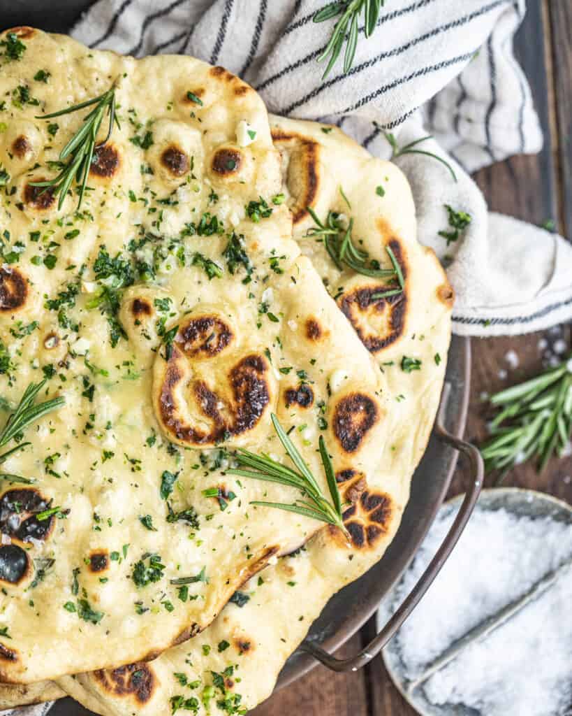 side view of rosemary garlic butter naan on a serving tray