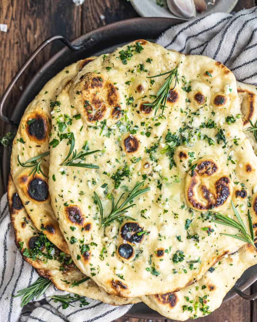 Rosemary Garlic Butter Naan topped with fresh rosemary on a serving tray