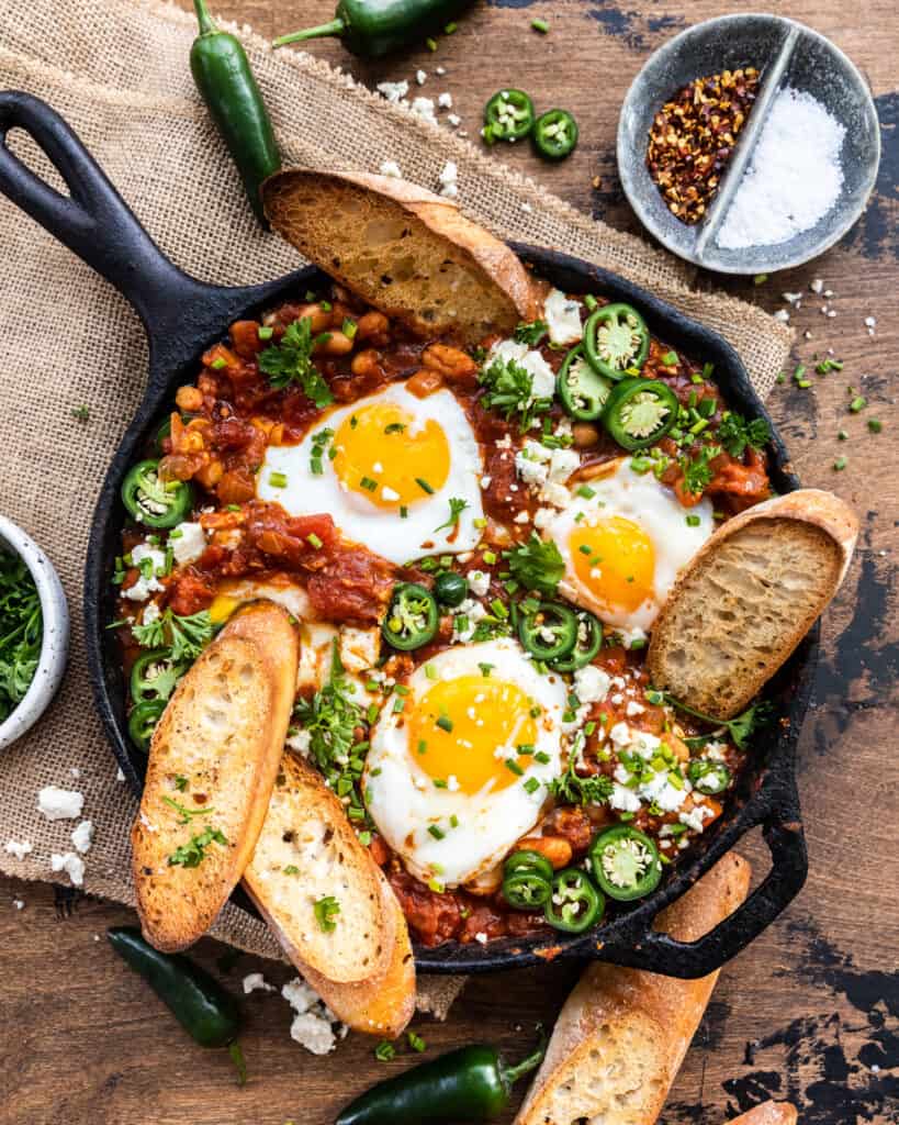 spicy white bean shakshuka in a cast iron skillet with toasted bread