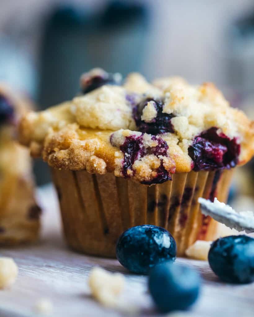 a blueberry crumb cake muffin with blueberries in front