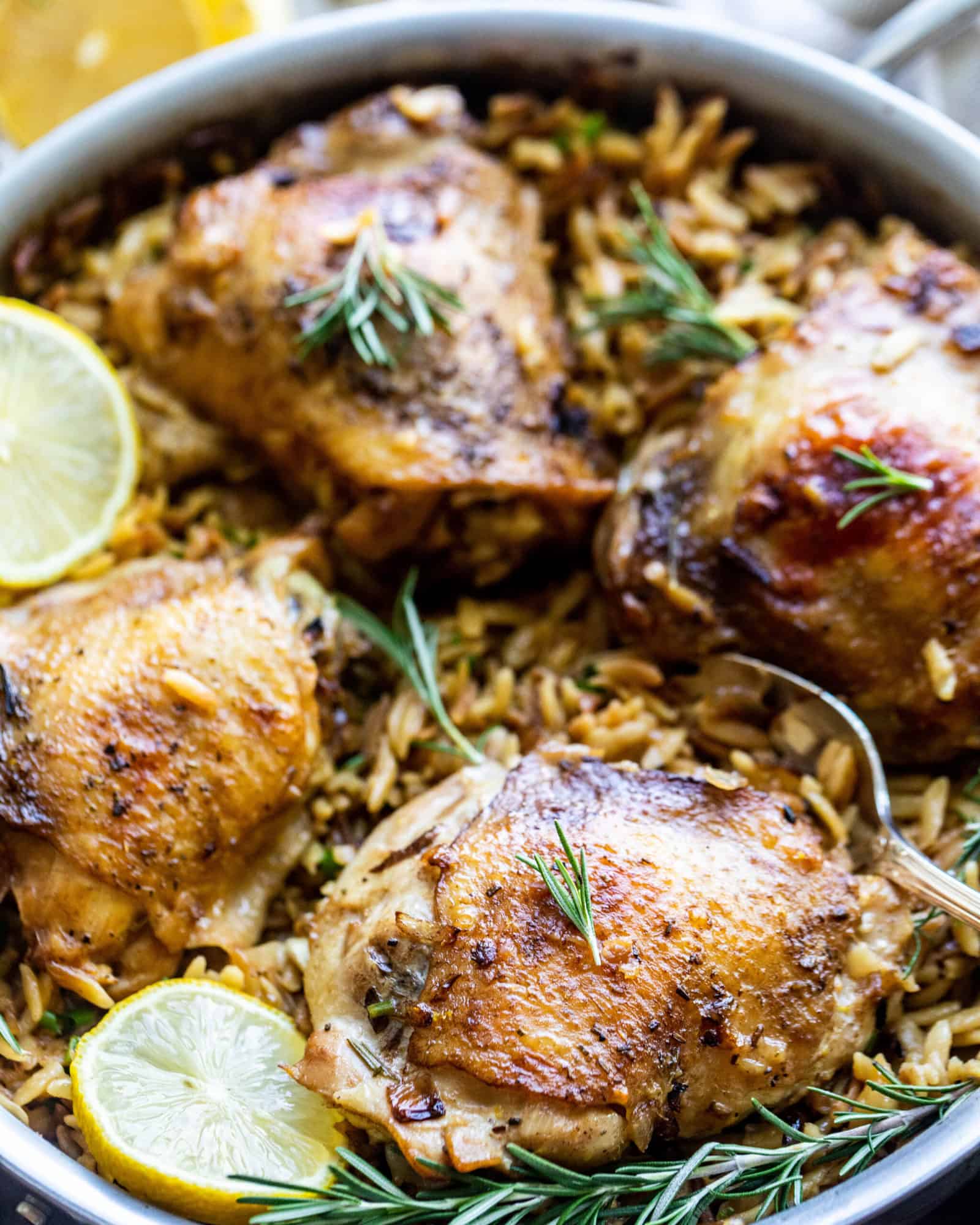 chicken and orzo in a large pan with lemons